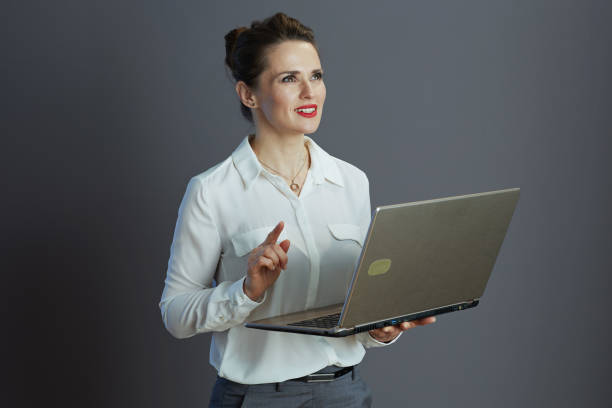 istock pensive stylish woman worker using laptop against grey 2159178525