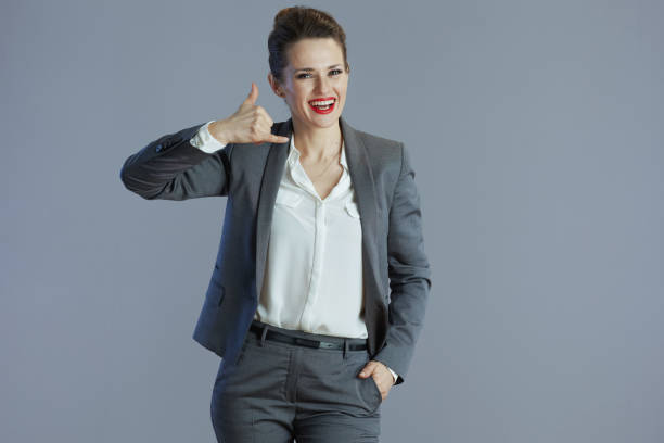 istock smiling woman worker showing call me gesture against gray 2159178557