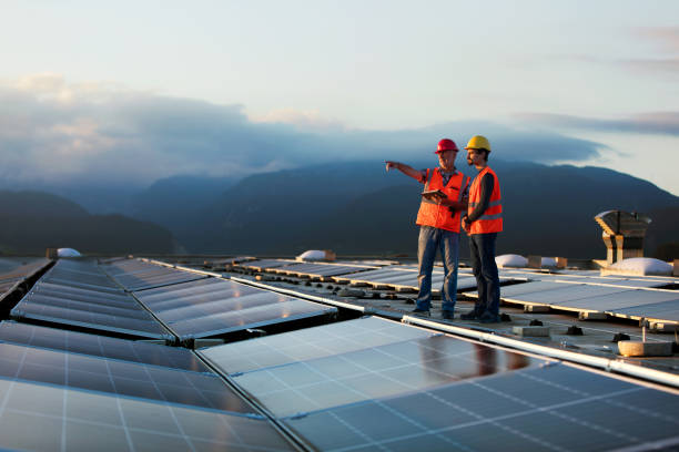 istock Technicians in reflective vests checking solar power plant installed on building roof 2159183156