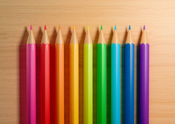 A row of colored pencils are lined up on a desk background