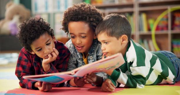 istock Children, book and reading on floor at school, learning and literacy knowledge or mind development. Boys, kids and storytelling for education, english and literature information on mat for language 2159187480