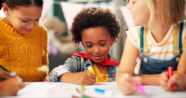 istock Happy children, drawing and paper with class in kindergarten for fun activity or coloring in classroom. Group of young elementary kids sketching colorful poster or sign for learning and development 2159187501