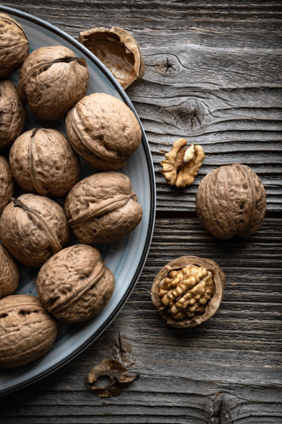 istock Walnut nuts and kernels in blue plate on old grunge wooden table 2159187530