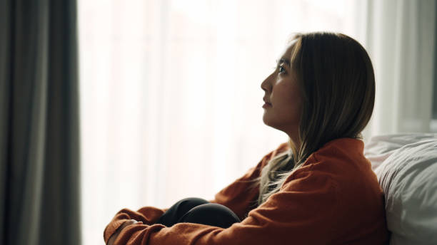 Woman depression hugging herself in bedroom.