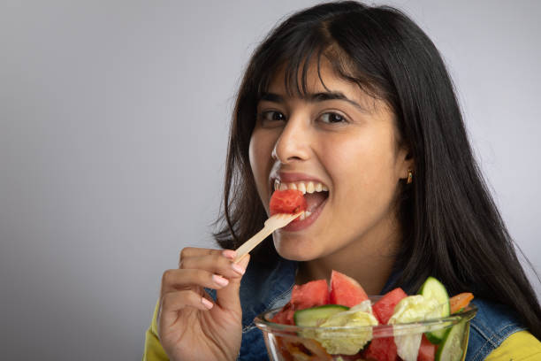 istock Woman smiling and eating fruit salad on gray background 2159190315