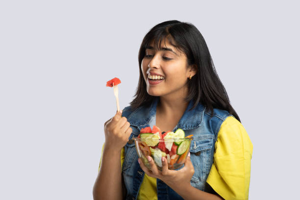 istock Woman smiling and eating fruit salad on gray background 2159190355