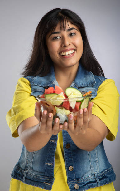 Smiling young woman with salad bowl