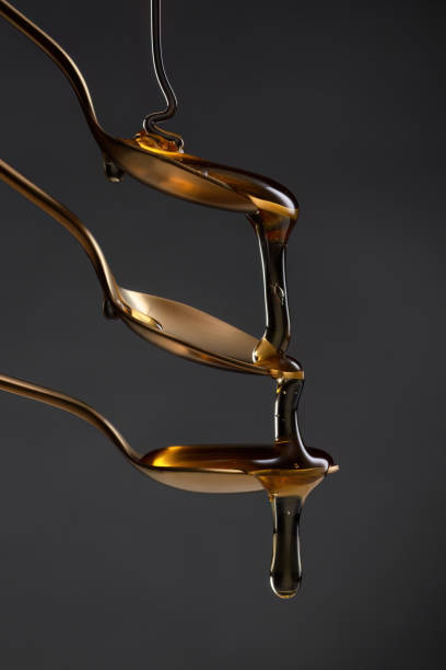 istock Golden spoons with pouring honey on a dark background. 2159190467