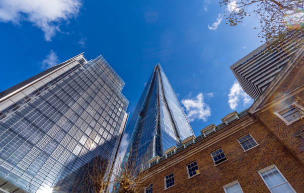 istock Low angle view of modern pyramid shaped glass skyscraper The Shard with blue sky and some clouds reflected in the windows of the buildings windows. London. United Kingdom. 2159198292