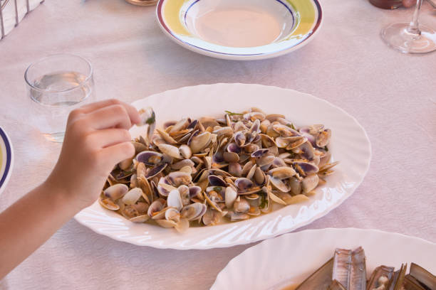 istock Hand taking from a tray with cooked razor clams 2159199715