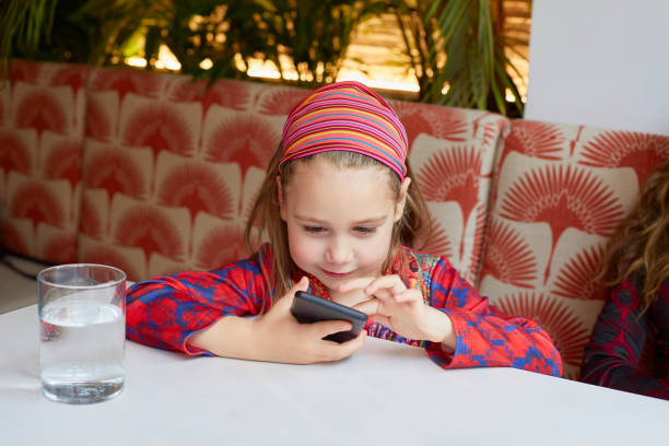 istock smiling girl touching a smartphone in a restaurant 2159199973