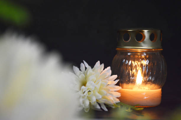 Sympathy card with white votive candle on dark background, copy space.