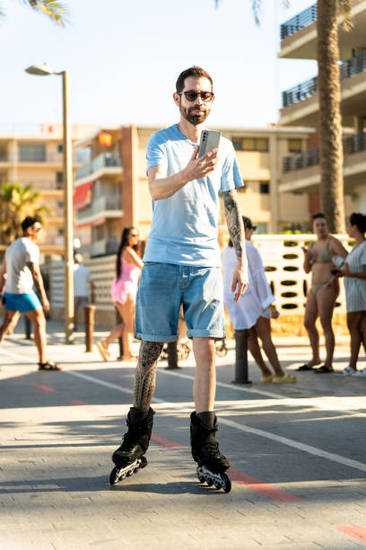 European man records himself with his cell phone while skating on the beach