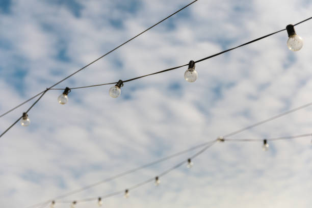 Light bulbs on a wire against the blue sky with white clouds.