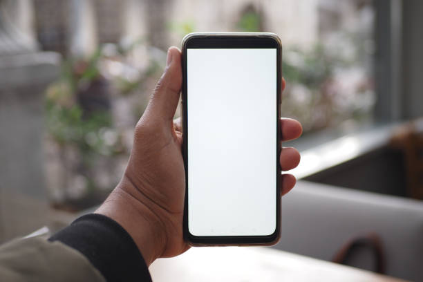 istock Hand holding smartphone with blank screen in urban cafe, symbolizing modern connected lifestyle 2159213623