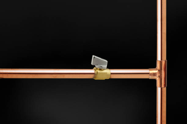 Copper plumbing pipe branch with a valve faucet on a black background