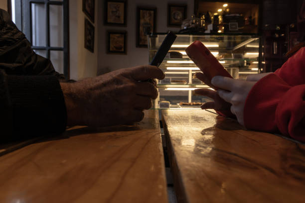 Old man's hand and young woman's hand holding smartphones