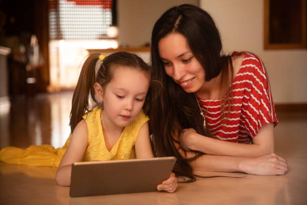 istock Young woman and girl child lying down using tablet 2159222406