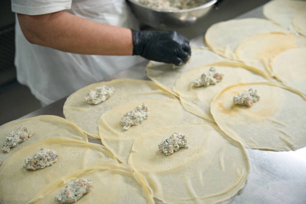 istock Worker puts fish filling on round pancakes 2159225013