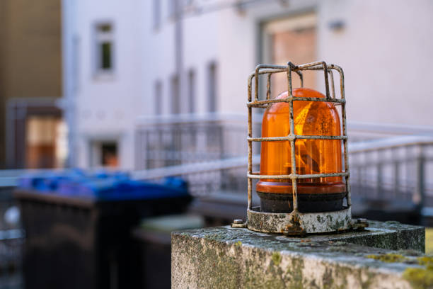 Close-up of an orange flashing warning ligh and a rusty grille on it. Focus on foreground.