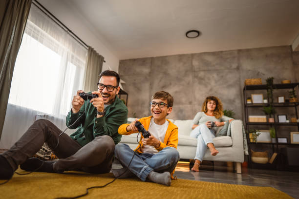 istock Dad and son play video games with joystick while mum wife watch them 2159238593