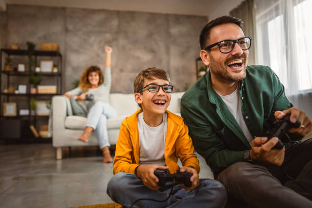 istock Dad and son play video games with joystick while mum wife watch them 2159238646