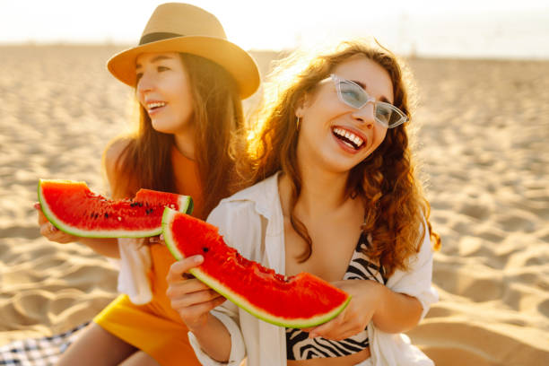 istock Two laughing women with watermelon on beach. 2159241207