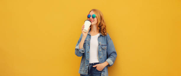 istock Modern stylish happy young woman drinking coffee posing on bright yellow background 2159242575