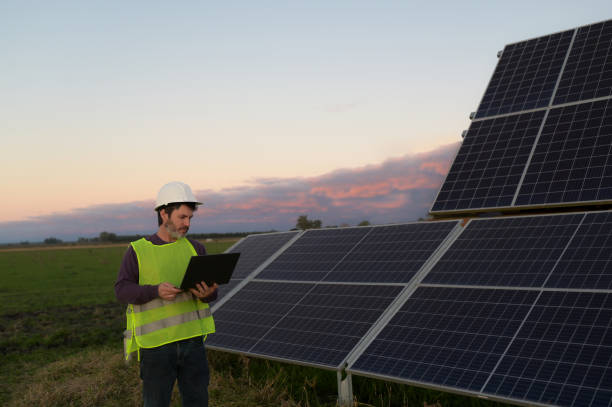 istock employee with laptop taking data next to solar panels 2159245249