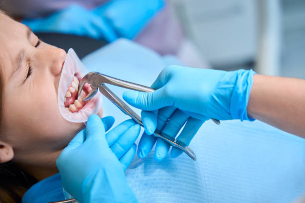Doctor removes a girls tooth with a special tool