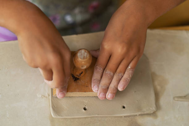 istock Child's hands in pottery-making process, pressing wooden tool into soft clay, creating piece of art, development of fine motor skills, discovery of one's own capabilities 2159250796