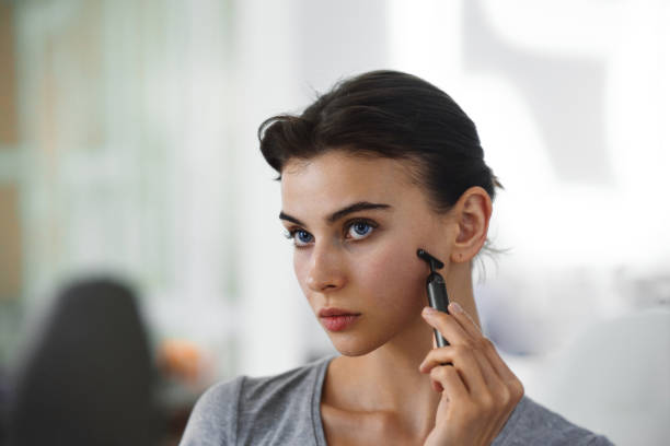 istock A young woman massages her face with gouache while looking in the mirror. 2159253346