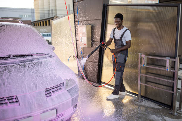 Skilled car wash professional sprays a car exterior with precision, using a foam cannon.