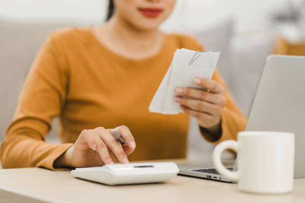 istock Focused woman calculating expenses using calculator and laptop at home, managing finances. 2159268124
