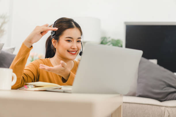 istock Woman wearing a headset, actively engaged in an online learning session with a teacher displayed on a computer screen, studying from home. 2159268136