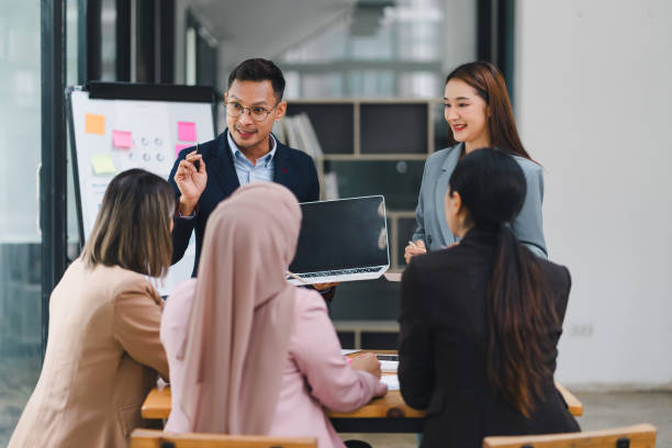 istock Diverse business team analyzing data and discussing strategies during an office meeting, using documents and a laptop. 2159268664