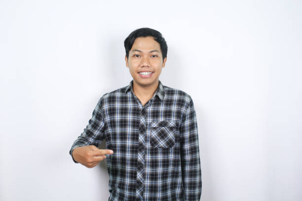 istock attractive asian man pointing finger to the middle with looking at camera isolated 2159276087