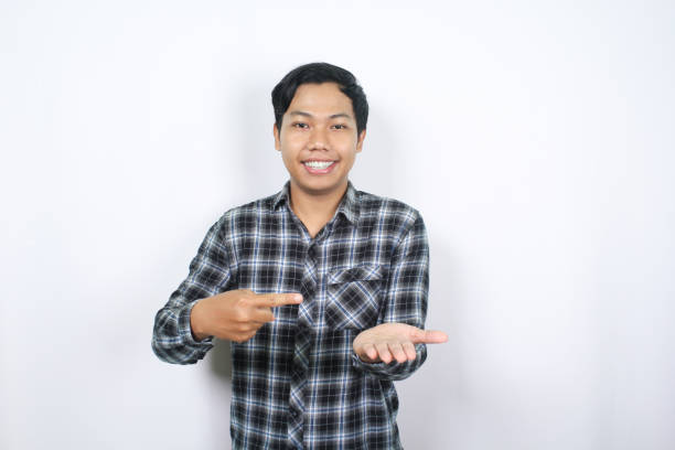 istock happy asian man standing on isolated background pointing finger to empty palm 2159276181