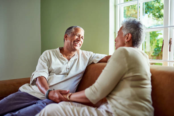 istock Talking, laughing and senior couple on sofa having conversation, bonding and holding hands. Elderly black man and woman relax, talk and laugh together in home enjoy retirement, having fun and in love 2159278633