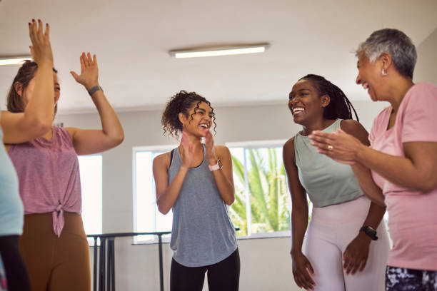 istock Low angle view of diverse students of different ages and female coach laughing and clapping hands after class in studio 2159278899