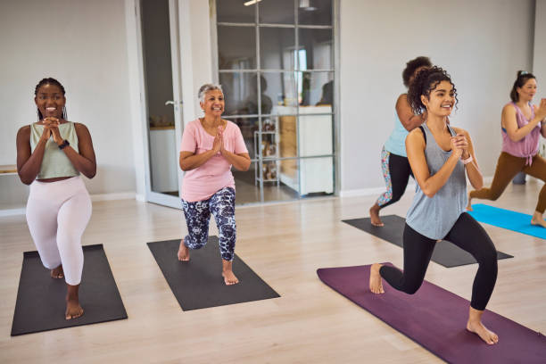 istock Cheerful young female yoga coach guiding diverse students, doing lunges with clasped hands in studio 2159279091