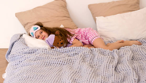 istock Girl in sleep mask with teddy bear lying on bed. 2159286609