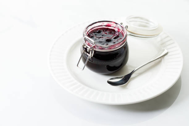 Jar of blueberry jam on white marble table background. Selective focus.