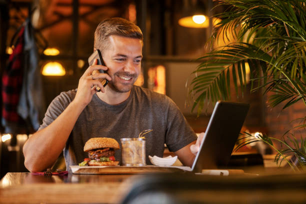 istock Smiling man having phone call and using tablet during his lunch break at restaurant. 2159293816