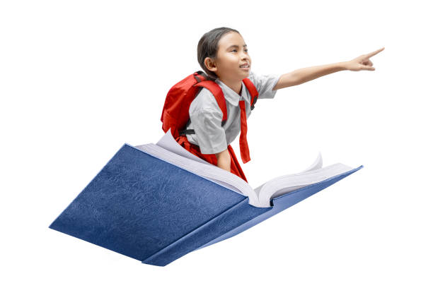 istock Asian schoolgirl with backpack flying on a book pointing at something with finger on white background 2159294468