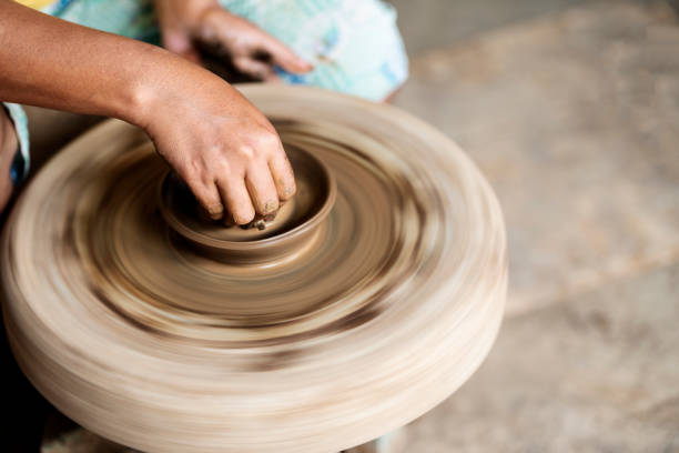 Human hand sculpting a craft from raw clay on the pottery wheel
