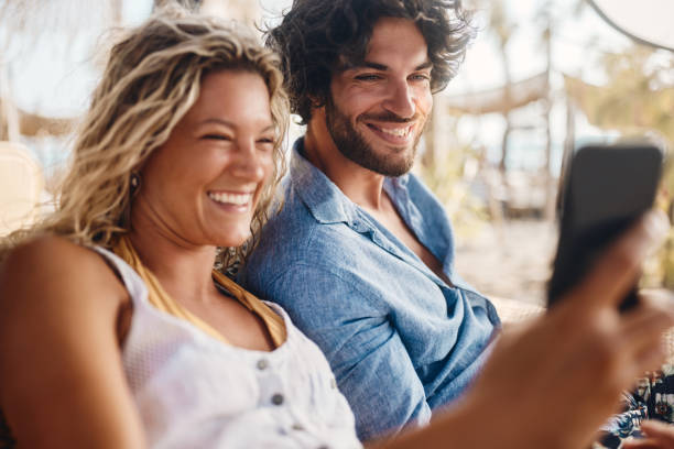 istock Happy couple using mobile phone on the beach. 2159295613