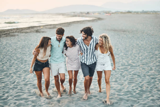 istock Young happy friends talking while walking embraced on the beach. 2159295667