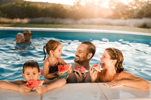 istock Happy family talking while eating watermelon in the pool. 2159296159
