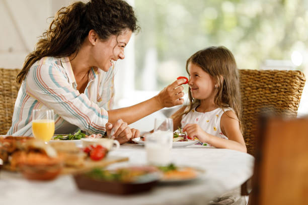 istock Happy mother having fun with her daughter during breakfast at dining table. 2159296310